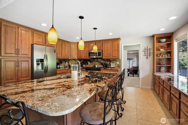 a kitchen with stainless steel appliances granite countertop a stove top oven a refrigerator a sink and white cabinets