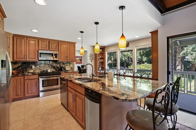 a kitchen with kitchen island granite countertop wooden cabinets and stainless steel appliances