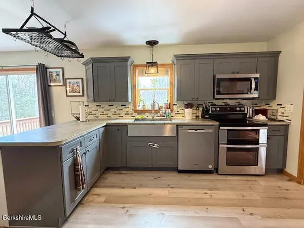 a kitchen with stainless steel appliances granite countertop a stove a sink and a microwave