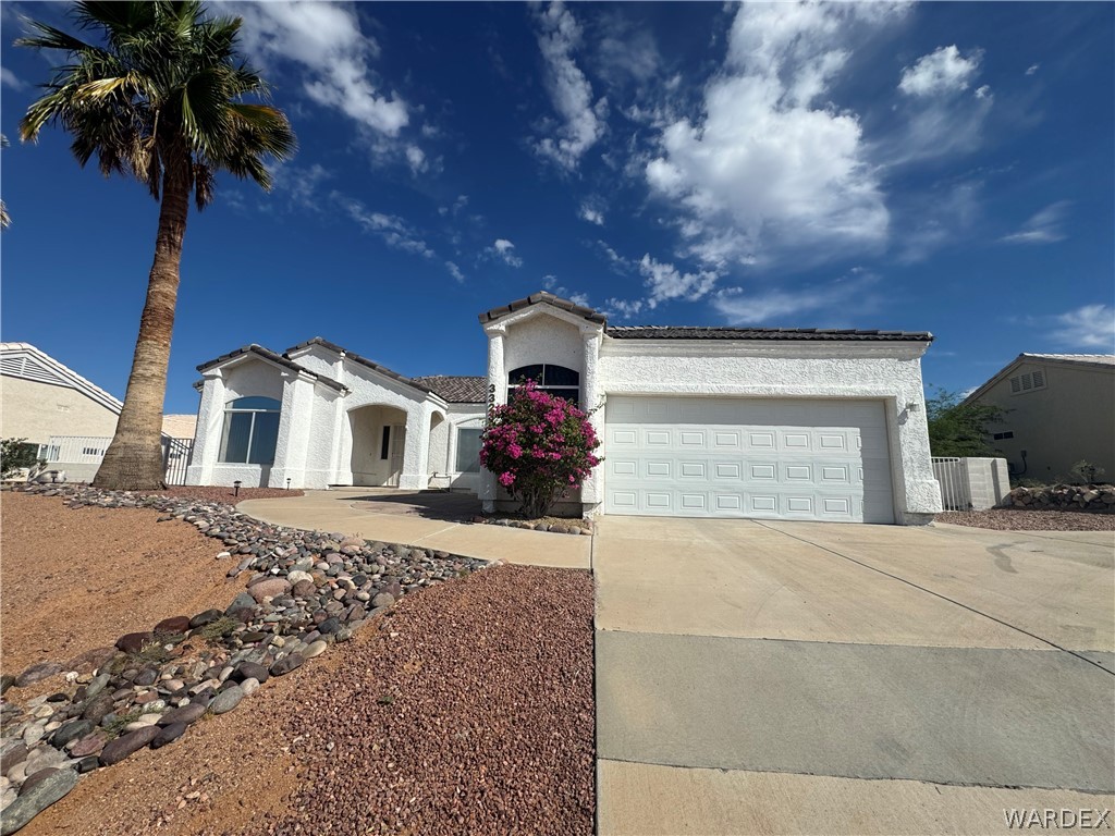 The property features a white stucco exterior, an attached garage, and a concrete driveway