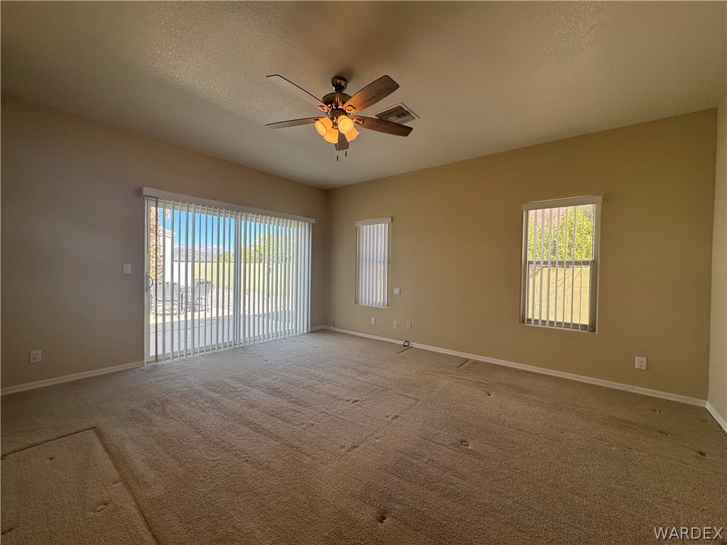 3323 North Ridge Avenue Bullhead City, AZ 86429 - Photo 12 of 24 This living space features a ceiling fan with integrated lighting, carpeted flooring, and sliding glass doors that open to a patio area