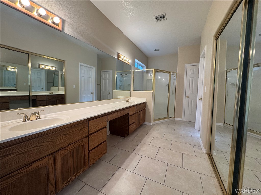 3323 North Ridge Avenue Bullhead City, AZ 86429 - Photo 14 of 24 Bathroom featuring dual sinks set in a long vanity with wood cabinetry, a large wall mirror, and tile flooring