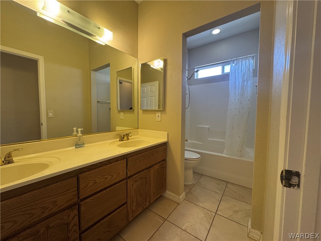 3323 North Ridge Avenue Bullhead City, AZ 86429 - Photo 16 of 24 Bathroom featuring a dual vanity with a light-colored countertop and wooden cabinetry, a large mirror, and tiled flooring