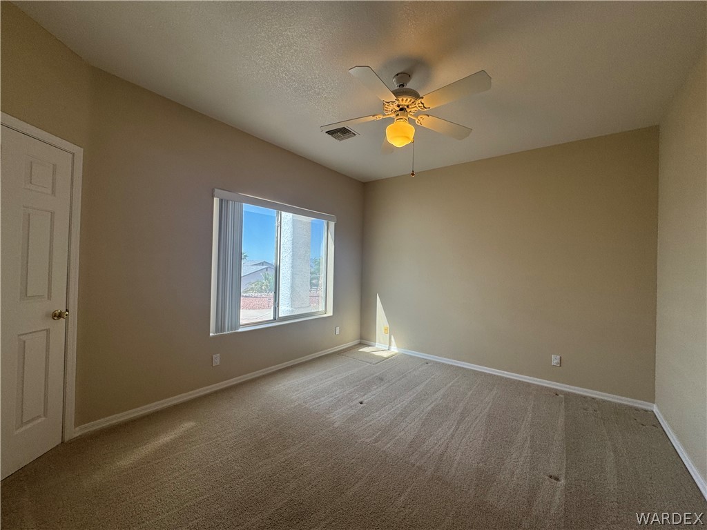 3323 North Ridge Avenue Bullhead City, AZ 86429 - Photo 17 of 24 This room features a neutral color palette, a ceiling fan with an integrated light fixture, a window with blinds, and carpeted flooring