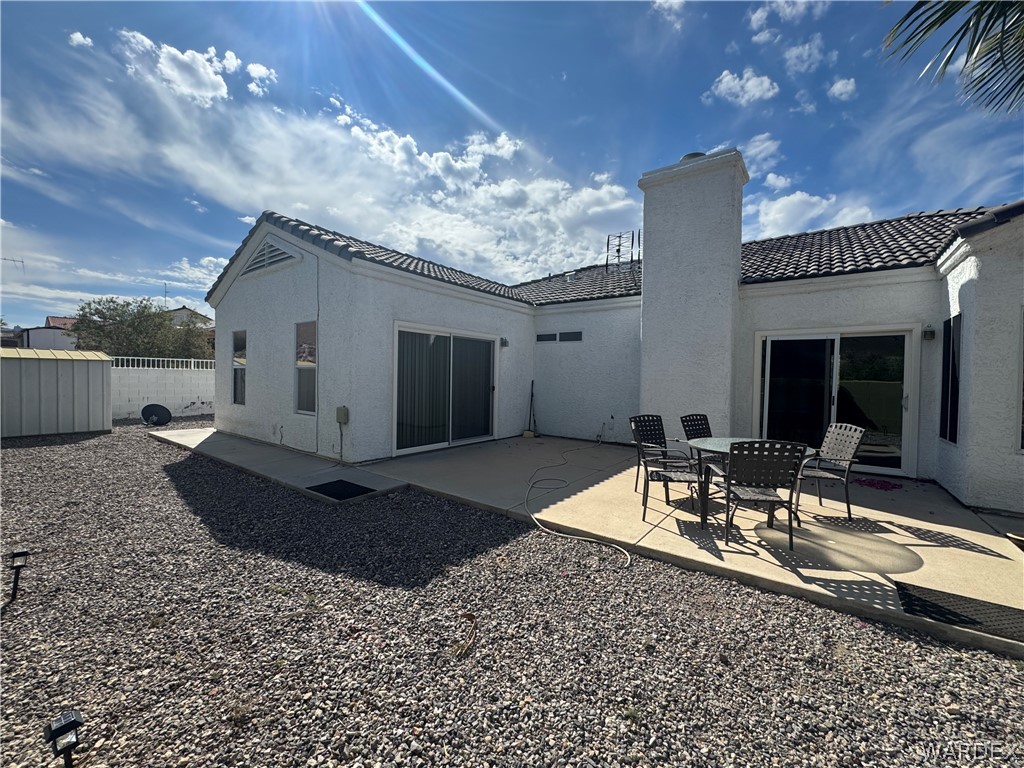3323 North Ridge Avenue Bullhead City, AZ 86429 - Photo 22 of 24 The property features a stucco exterior, a tiled roof, and an outdoor patio area with direct access via sliding glass doors