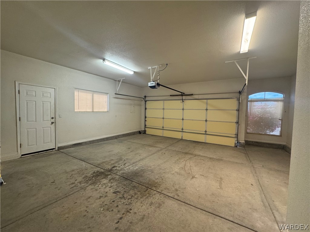3323 North Ridge Avenue Bullhead City, AZ 86429 - Photo 23 of 24 The property features a garage with a roll-up door, a side entry door, and two windows providing natural light