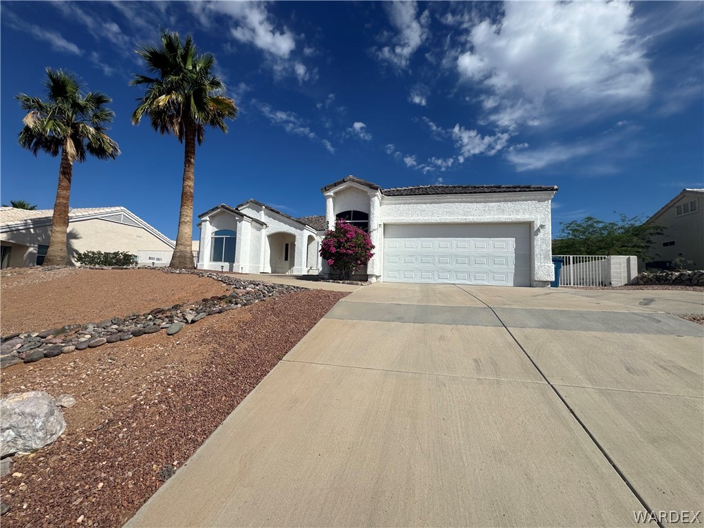 3323 North Ridge Avenue Bullhead City, AZ 86429 - Photo 3 of 24 The property features a white stucco exterior, an attached garage, and a concrete driveway