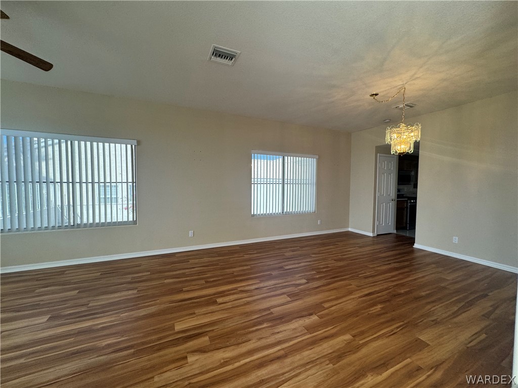 3323 North Ridge Avenue Bullhead City, AZ 86429 - Photo 4 of 24 Spacious room featuring wood-look flooring, neutral wall tones, and multiple windows with blinds