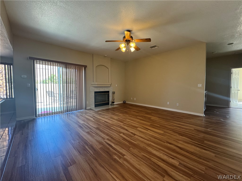 3323 North Ridge Avenue Bullhead City, AZ 86429 - Photo 6 of 24 Spacious living area featuring warm-toned flooring, a fireplace with a decorative mantel, and a ceiling fan