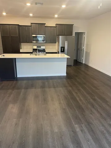 a large kitchen with stainless steel appliances a large counter top a stove and a wooden floors