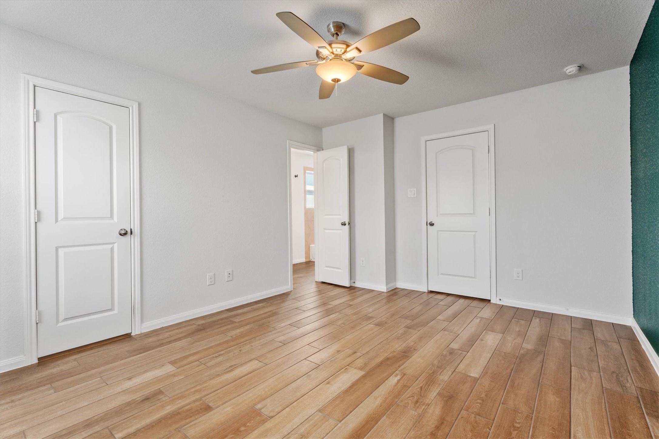 12912 Lake Conroe Bay Road Willis, TX 77318 - Photo 16 of 33 an empty room with wooden floor and a ceiling fan