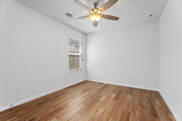 a view of a room with wooden floor and a ceiling fan
