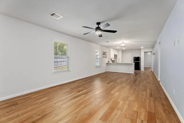 a view of empty room with wooden floor and windows