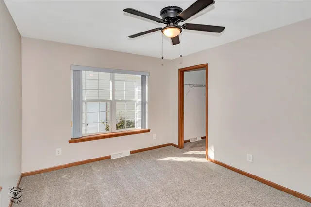 an empty room with chandelier fan and windows