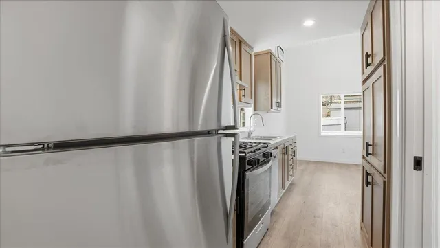 a kitchen with stainless steel appliances granite countertop a refrigerator a sink and white cabinets