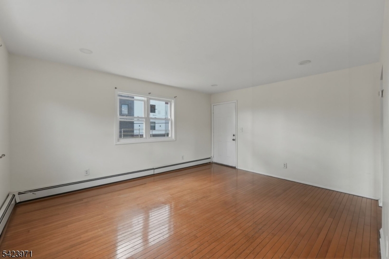 172 Carroll Street Paterson, NJ 07501 - Photo 16 of 48 a view of an empty room with wooden floor and a window