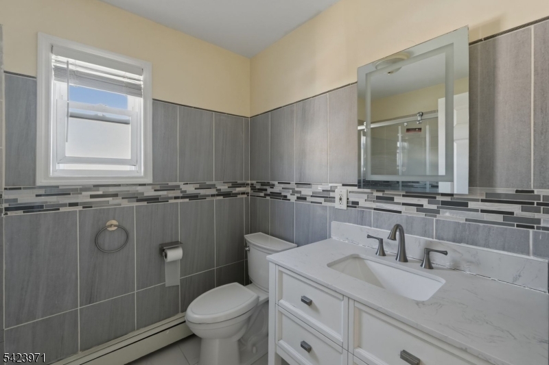 172 Carroll Street Paterson, NJ 07501 - Photo 23 of 48 a bathroom with a granite countertop sink a toilet and a mirror