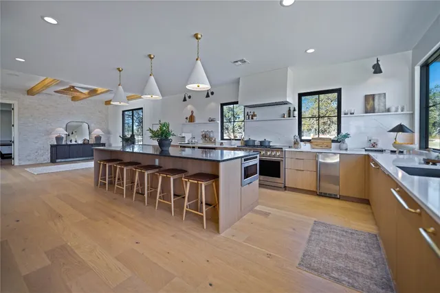 a large kitchen with kitchen island a sink a stove a dining table and chairs