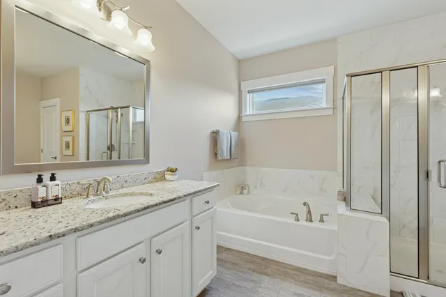 a bathroom with a granite countertop sink mirror bathtub and double