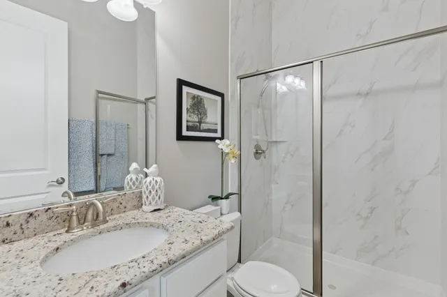 a bathroom with a granite countertop sink toilet and shower