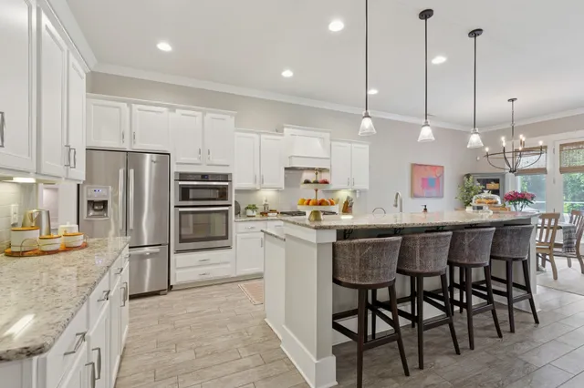 a kitchen with a refrigerator a oven and chairs