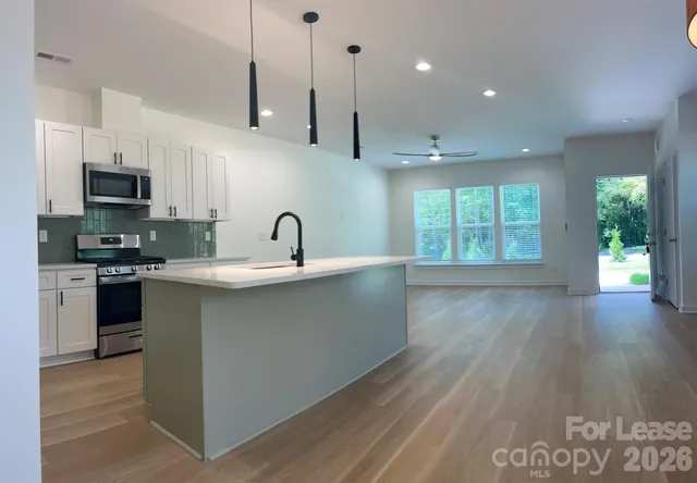 a kitchen with stainless steel appliances granite countertop a sink a stove and a wooden floors