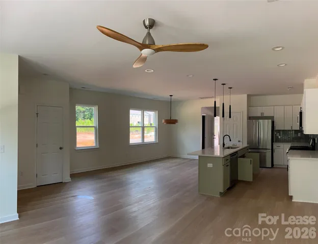 a view of a kitchen with fridge and wooden floor