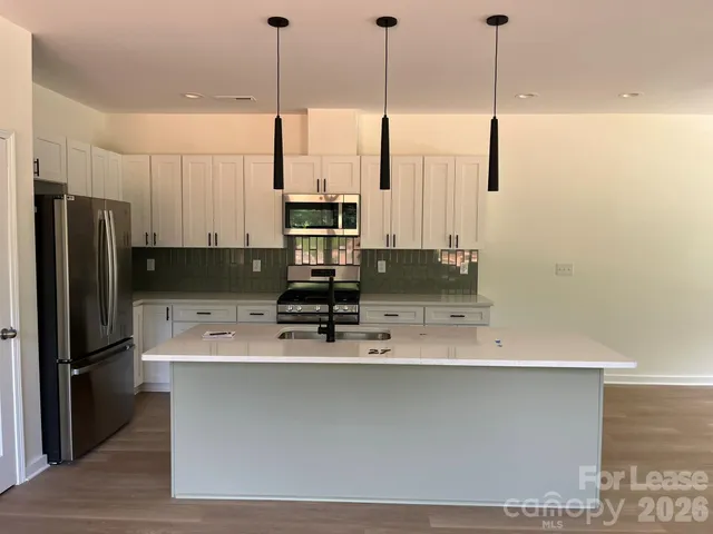 a kitchen with stainless steel appliances granite countertop a sink a refrigerator a stove and a refrigerator