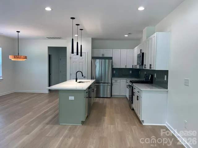 a kitchen with kitchen island a sink stainless steel appliances and cabinets