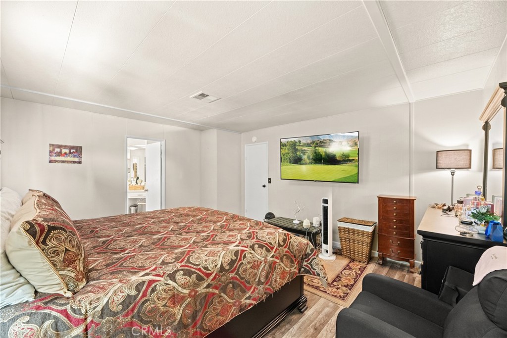 2964 Silver Oak Way Hemet, CA 92545 - Photo 33 of 60 a bedroom with a bed table chair and painting on the wall