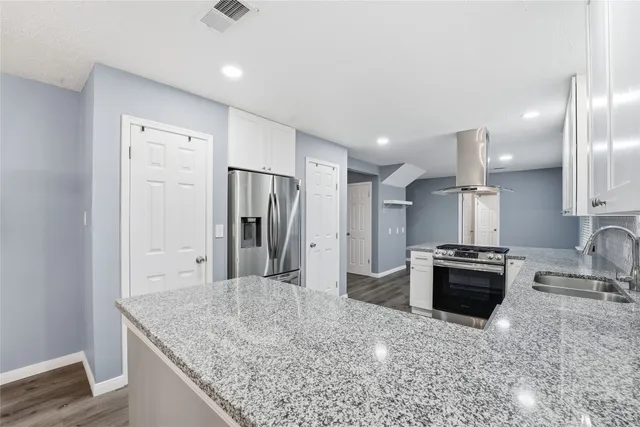 a kitchen with granite countertop a sink stove and refrigerator