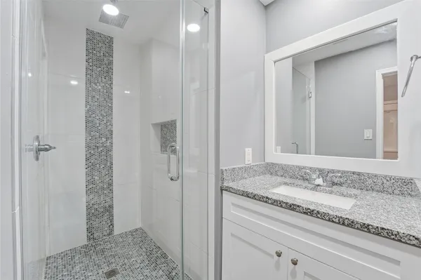 a bathroom with a granite countertop sink and shower