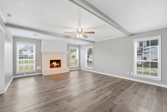 a view of an empty room with wooden floor fireplace and a window