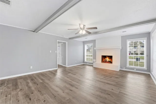 a view of an empty room with a window and wooden floor