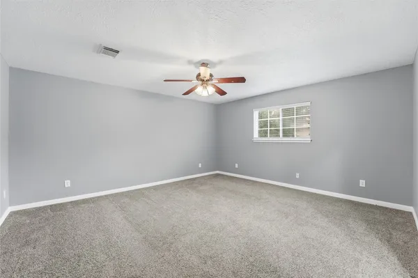 a view of an empty room with a ceiling fan and window