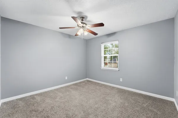 an empty room with windows and fan