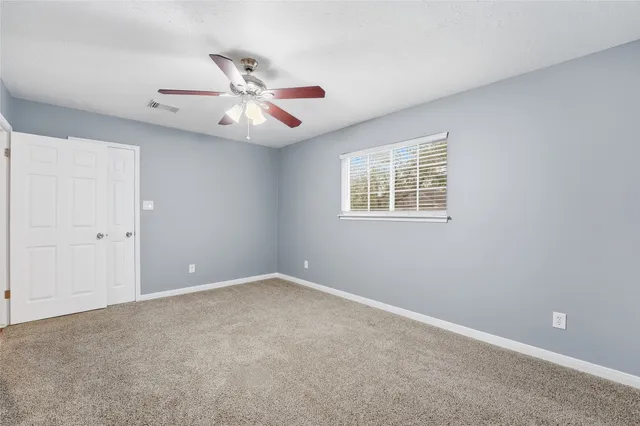 an empty room with ceiling fan and window