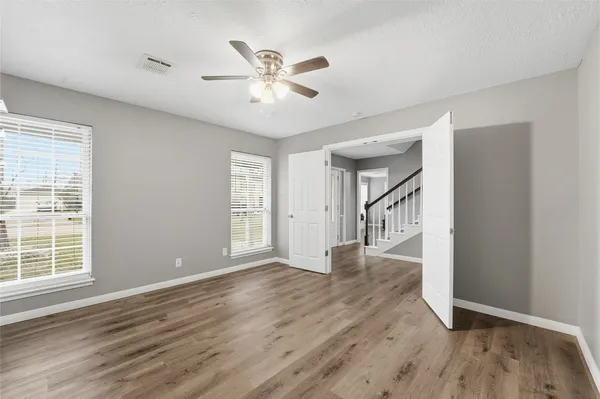 a view of an empty room with wooden floor and a window