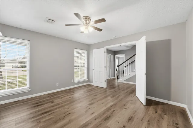 a view of an empty room with wooden floor and a window