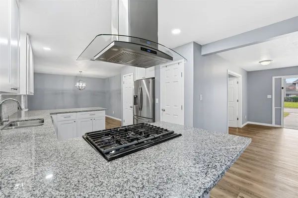 a kitchen with kitchen island granite countertop stainless steel appliances a sink stove and refrigerator