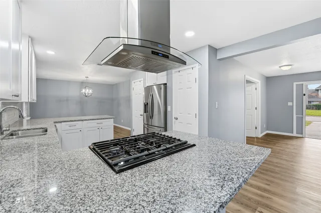 a kitchen with kitchen island granite countertop stainless steel appliances a sink stove and refrigerator