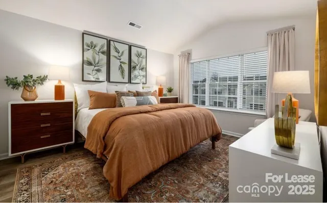 a bedroom with a bed a dresser and a large window