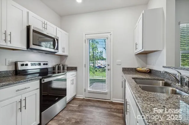 a kitchen with stainless steel appliances granite countertop a sink stove and microwave