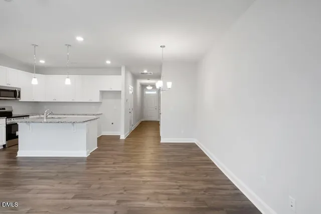 a view of kitchen with kitchen island a sink wooden floor and stainless steel appliances