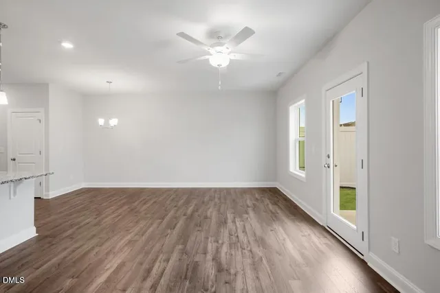 an empty room with wooden floor and a ceiling fan