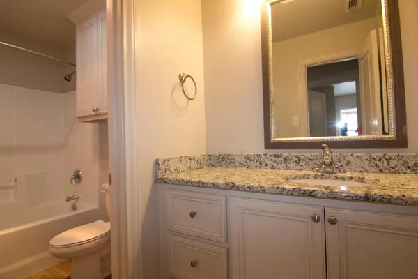 a bathroom with a granite countertop sink toilet and shower