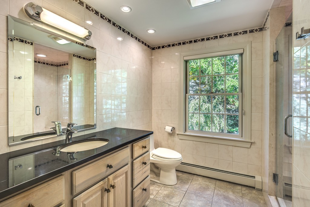 34 Leslie Road Winchester, MA 01890 - Photo 22 of 26 a bathroom with a granite countertop sink a toilet a mirror and a window