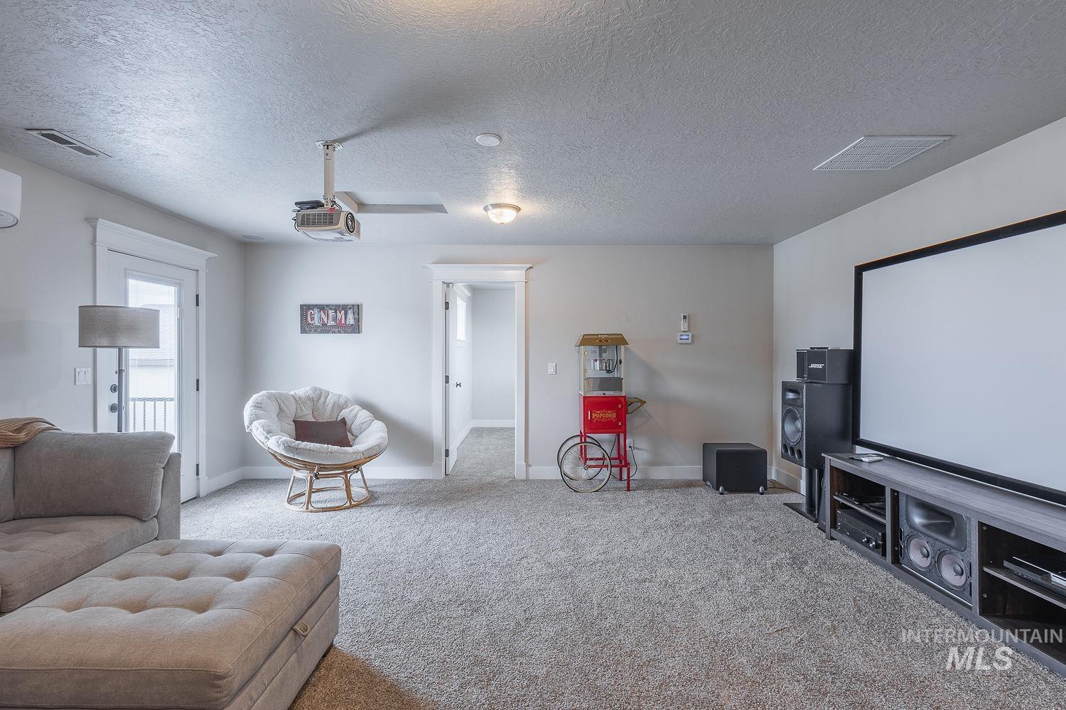 8077 Star Pass Ridge Road Nampa, ID 83686 - Photo 30 of 37 Dedicated entertainment space featuring a large projection screen, mounted projector, and neutral-toned carpeting