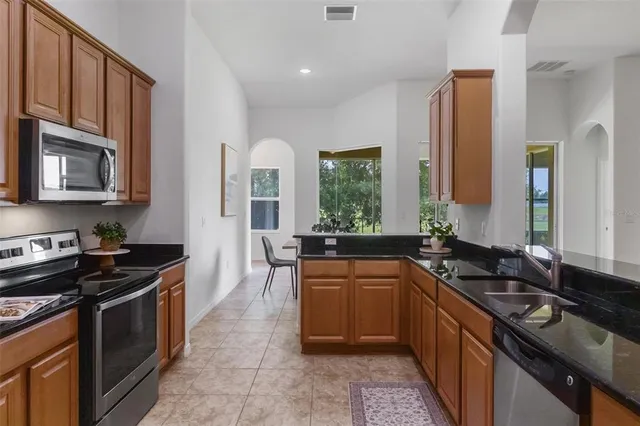 an empty room with chandelier fan and refrigerator