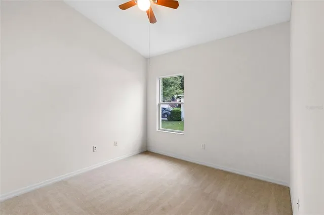 an empty room with a window and a ceiling fan